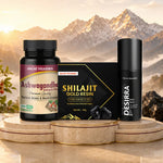 Three JAGAT PHARMA products displayed together on a set of round stone pedestals against a dramatic mountain backdrop: an Ashwagandha supplement bottle, a black Shilajit Gold Resin box, and a black Desirra spray bottle.